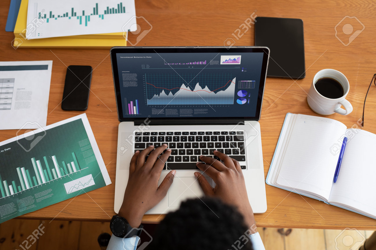 Business analyst reviewing analytics dashboard with charts and financial metrics displayed on laptop screen at desk